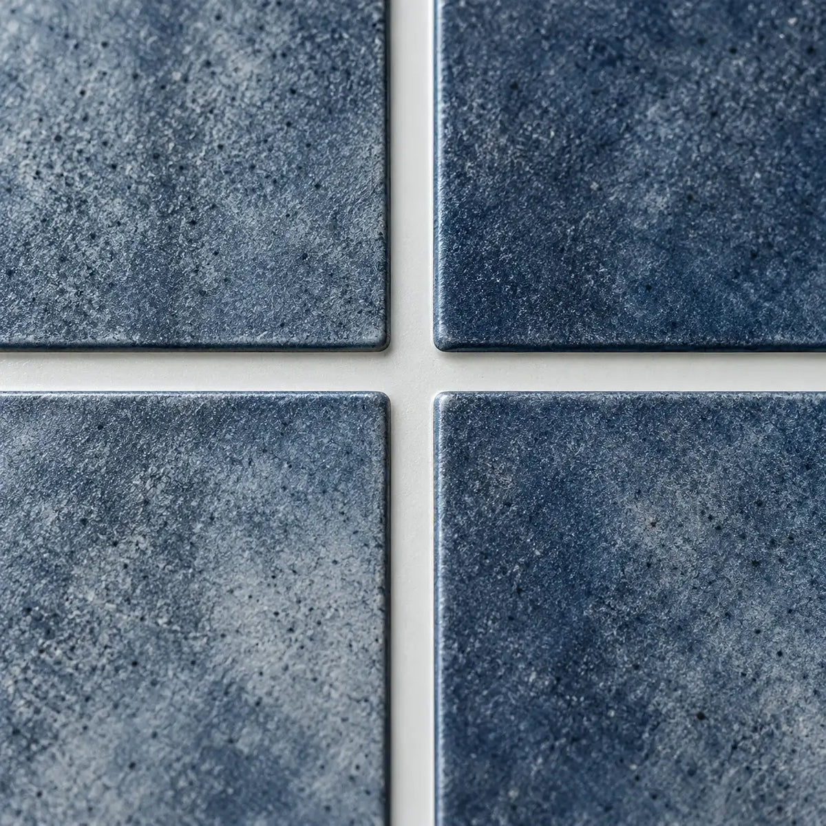 Gros plan sur les baguettes bleu indigo texturées du carrelage adhésif Oceana et leurs joints blancs
