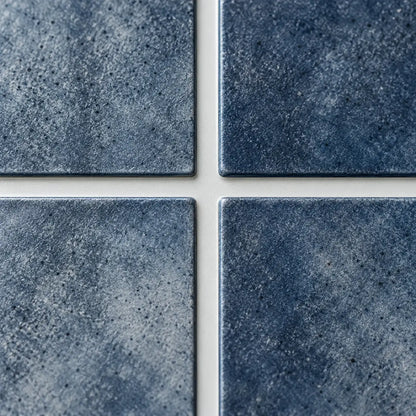 Gros plan sur les baguettes bleu indigo texturées du carrelage adhésif Oceana et leurs joints blancs