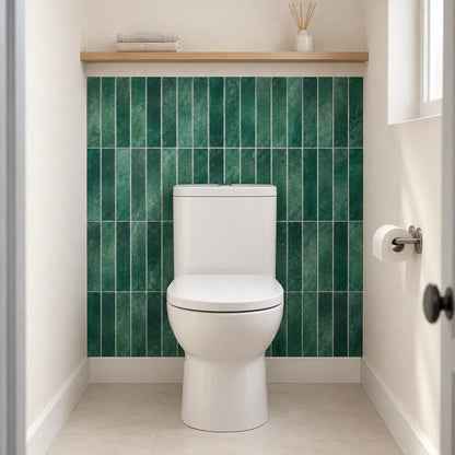 Mur des toilettes habillé de carrelage adhésif vert émeraude Esmera derrière la cuvette, étagère en bois au-dessus
