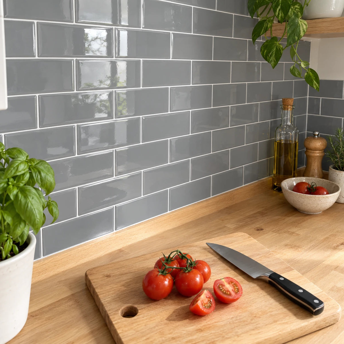 Plan de travail en bois avec planche à découper et tomates devant une crédence en carrelage adhésif métro gris