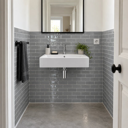 Salle de bain étroite avec carrelage adhésif métro gris à mi-hauteur, lavabo suspendu blanc et miroir à cadre noir
