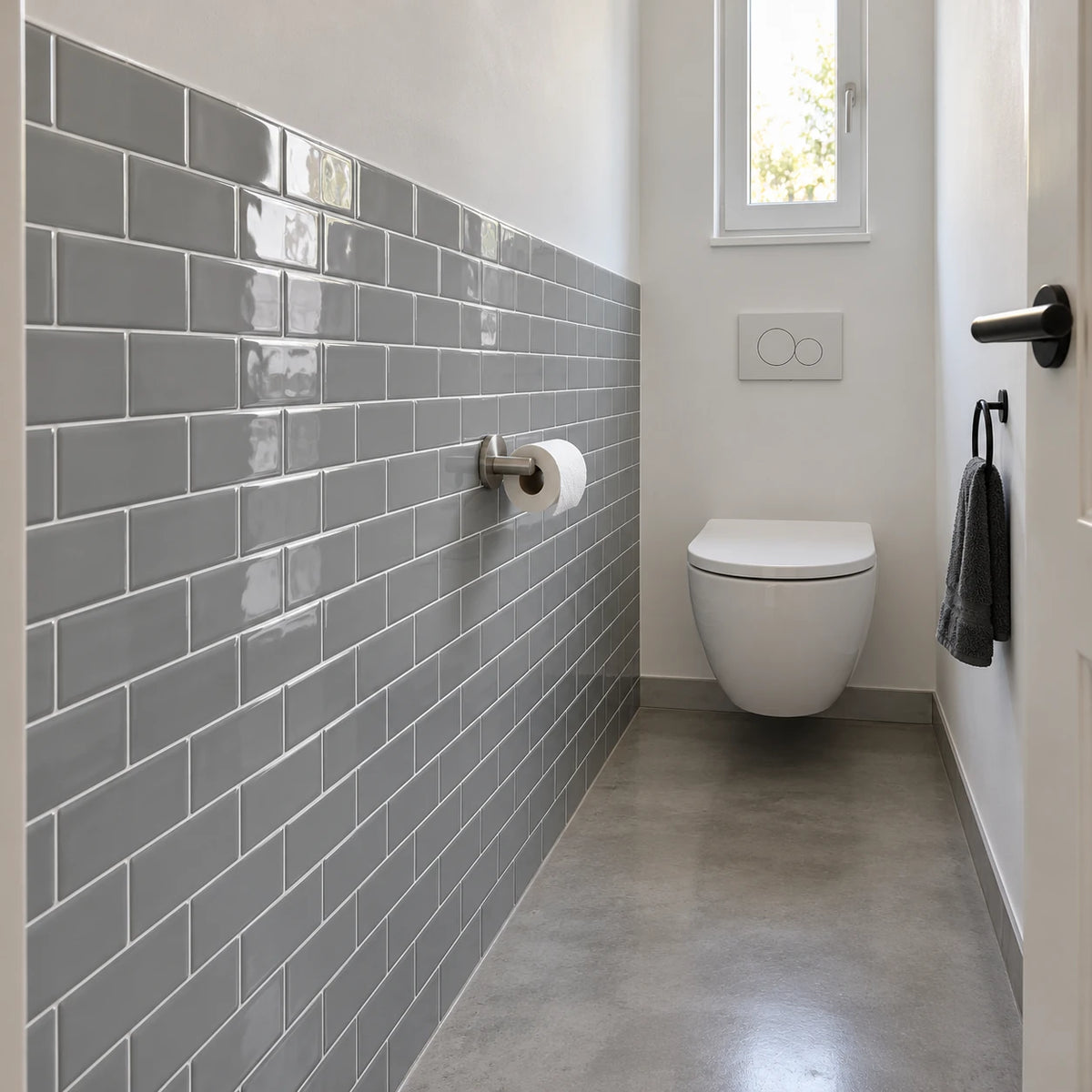 Toilettes en longueur avec mur en carrelage adhésif métro gris, WC suspendu et sol en béton ciré