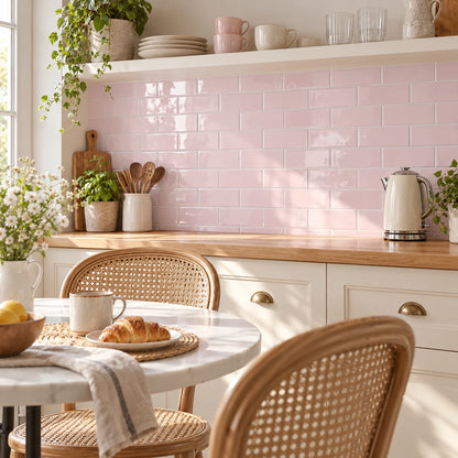 Coin repas avec table bistrot et chaises cannées devant un mur en carrelage adhésif métro rose poudré et une étagère blanche