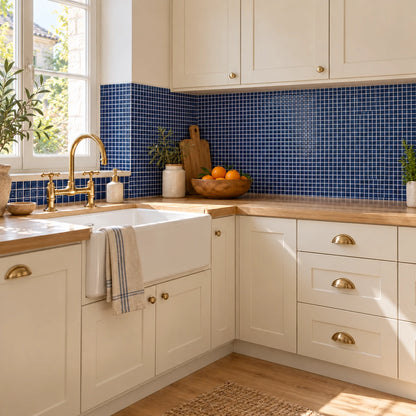 Grande cuisine aux façades crème et poignées en laiton avec crédence en carrelage adhésif mosaïque bleu marine