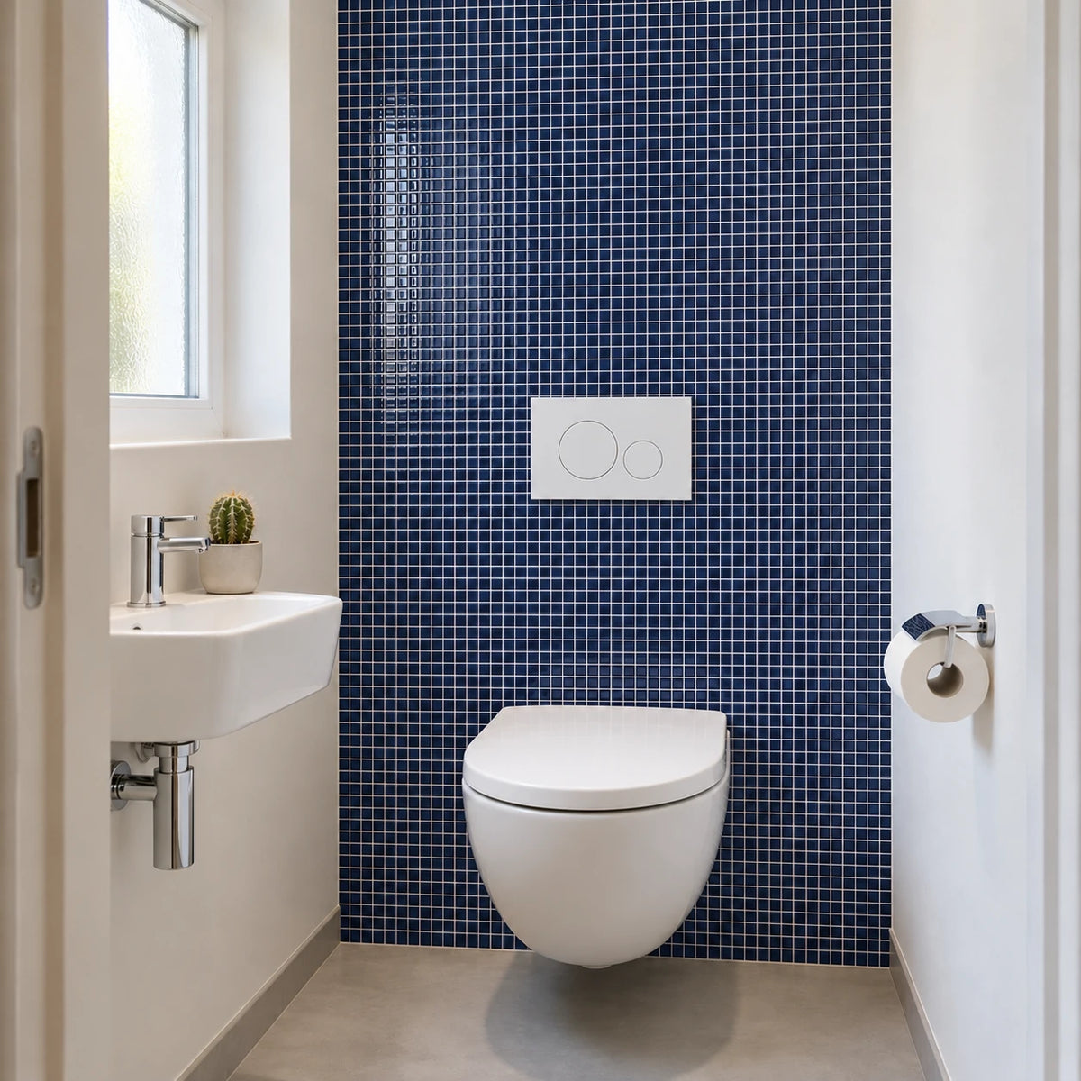 Toilettes avec WC suspendu, lave-mains et carrelage adhésif mosaïque bleu marine sur toute la hauteur du mur