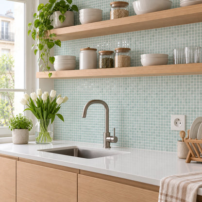 Cuisine lumineuse avec carrelage adhésif mosaïque vert d'eau sous des étagères en chêne, évier inox et bouquet de tulipes blanches