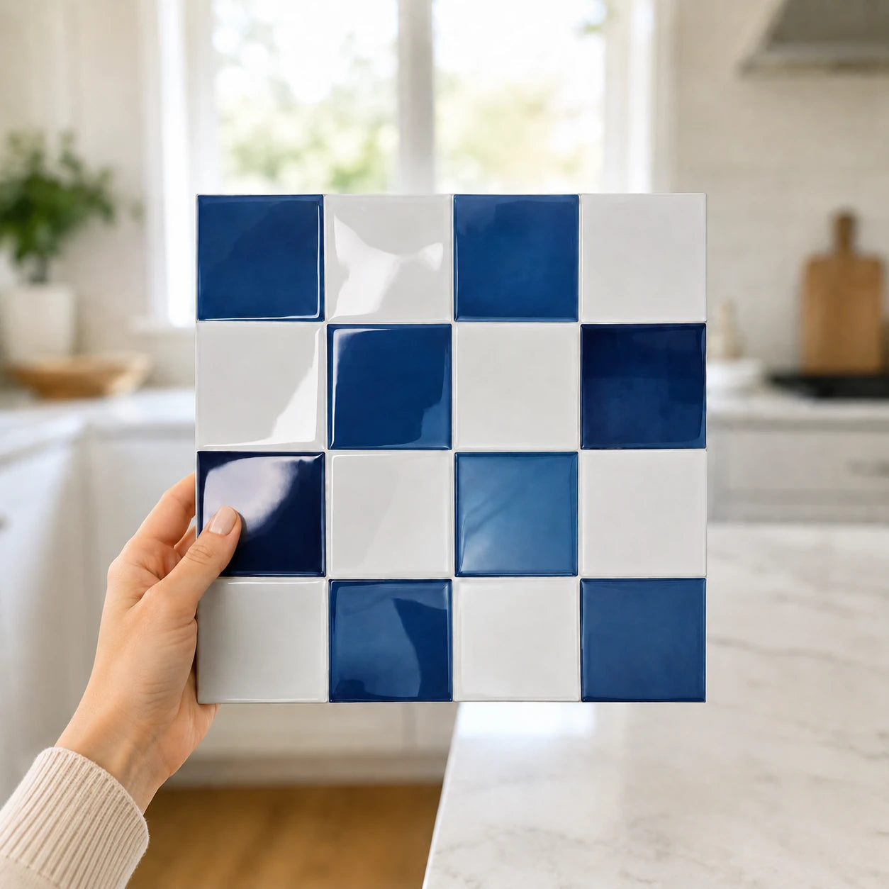 Main tenant une plaque de carrelage adhésif 3D bleu saphir Cobalta de 26,7 cm dans une cuisine