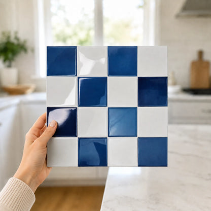 Main tenant une plaque de carrelage adhésif 3D bleu saphir Cobalta de 26,7 cm dans une cuisine