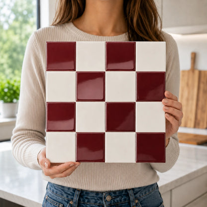 Femme tenant une plaque de carrelage adhésif 3D bordeaux Vermilio de 26,7 cm dans une cuisine