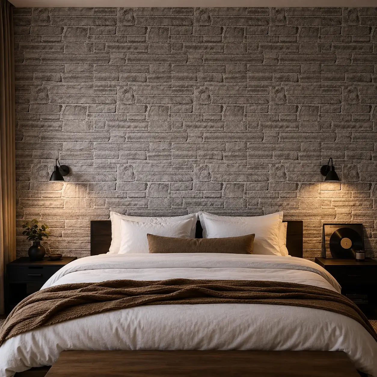 Mur de chambre habillé du panneau mural Ardesia effet pierre grise, derrière un lit double avec appliques noires.