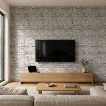 Mur de salon habillé du panneau mural Ardesia effet pierre grise, avec télévision murale, meuble TV en bois clair et décoration minimaliste.